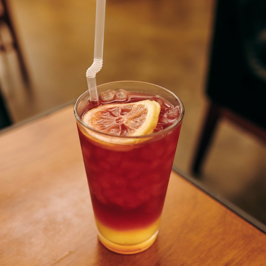 Iced red hibiscus tea with a lemon slice in a tall glass.