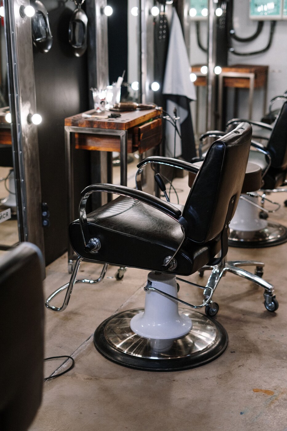 Black leather salon chairs in front of mirrors, photographed by cottonbro studio. Stock photography for this fictional demo.
