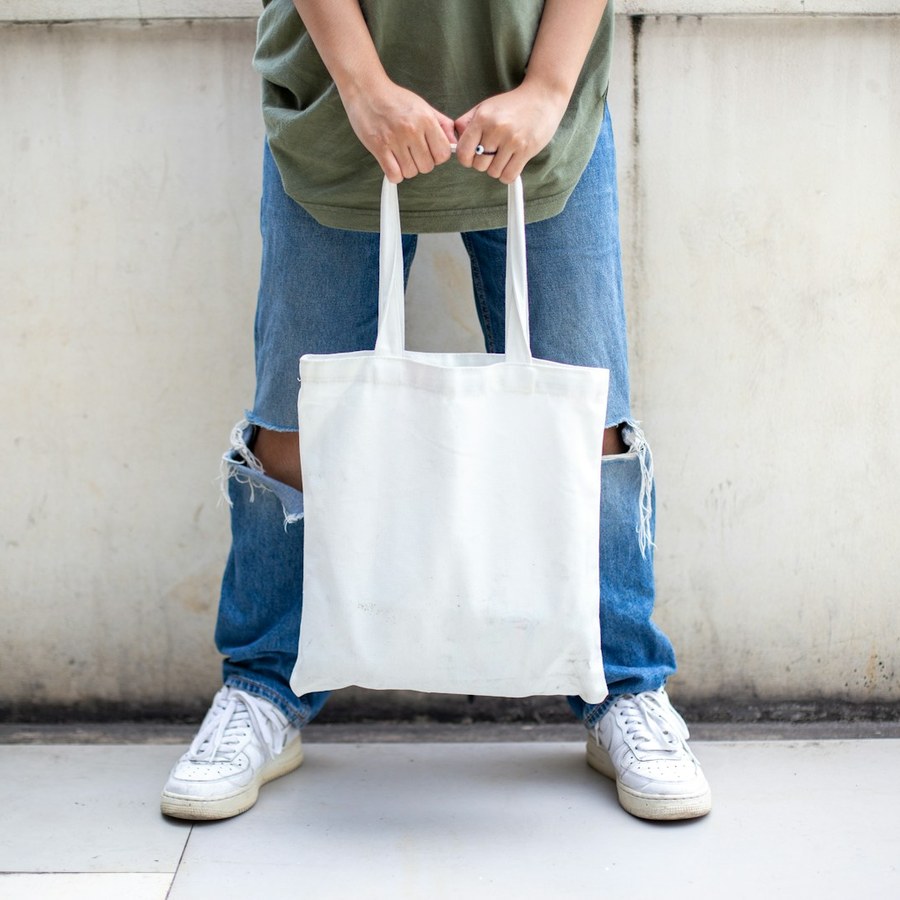 a person holding a plain white tote bag